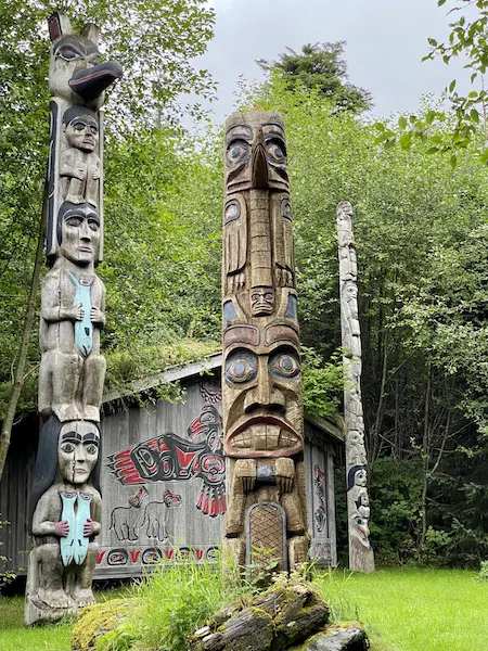 Two totem poles beside a clan house